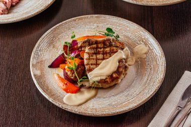 Ahşap bir masada sebzeli ızgara et ve sos. 