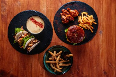 Kızarmış hamburger, patates kızartması ve ahşap masada sebze.