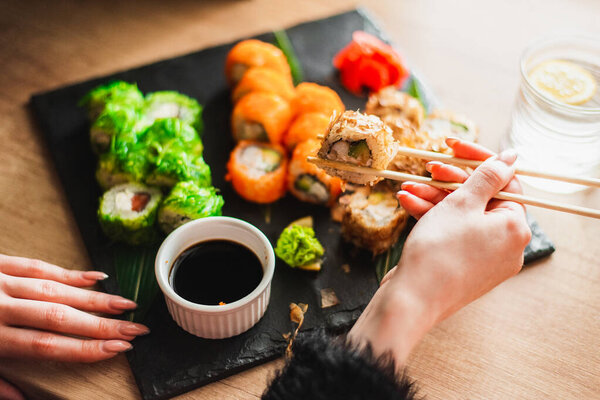 woman eating sushi with soy sauce on wooden table