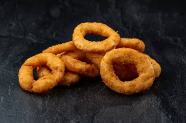 Siyah arkaplanda kızarmış soğan halkaları