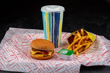 İçkili hamburger ve siyah arka planda patates kızartması.