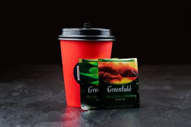 DZ burger etiketli kağıt bardak ve tahta arka planda iki paket çay.