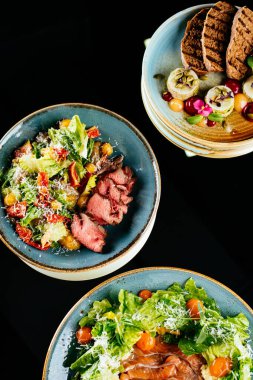 Tavuklu salata, sebze ve soslu siyah arka plan..