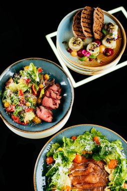 Siyah arka planda tavuk, sebze ve peynirli salata