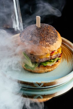 Ahşap bir arka planda pastırmalı ve sebzeli hamburger.