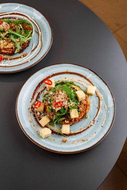 Kızarmış tavuk, sebzeli ve soslu beyaz tabak.