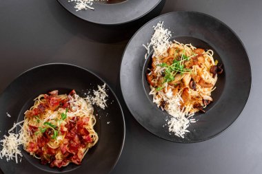 Siyah arka planda etli ve sebzeli makarna.