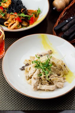 Beyaz tabakta deniz ürünleri ve sebzeli makarna.