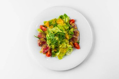 Tavuklu salata, domates ve beyaz tabakta marul.