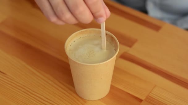 Close-up van mannelijke hand met stok interfereert met ambachtelijke kop met koffie op houten tafel — Stockvideo