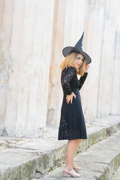 Retrato completo de mujer hermosa en traje de bruja negro para halloween con sombrero sobre fondo gris —  Fotos de Stock