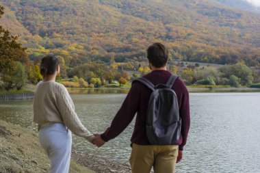 Geriye dönüp bakınca, örgü süveter giymiş bir çift, sonbahar ormanlarında el ele tutuşuyorlar.