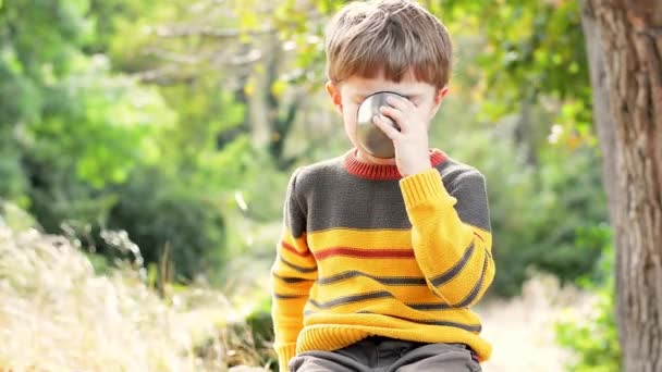 Stylowy piękny chłopczyk w przytulnym swetrze pije herbatę z termosu jesień — Wideo stockowe