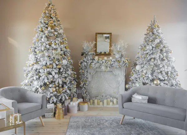 Όμορφο κομψό διακοσμημένο εσωτερικό δύο χριστουγεννιάτικα δέντρα με τζάκι και γκρι καναπέδες και δώρα Εικόνα Αρχείου
