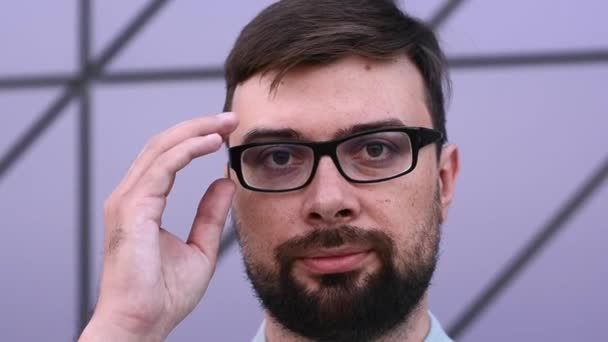 Stylish man takes off his glasses for vision directly to the camera on the street near the building — Wideo stockowe