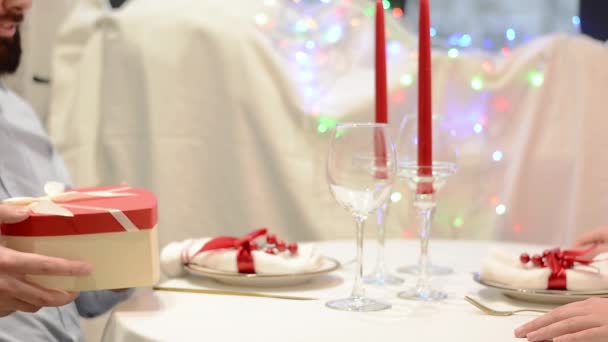 Close-up of a boyfriend giving a present to his girlfriend on a date in a valentines restaurant — Αρχείο Βίντεο