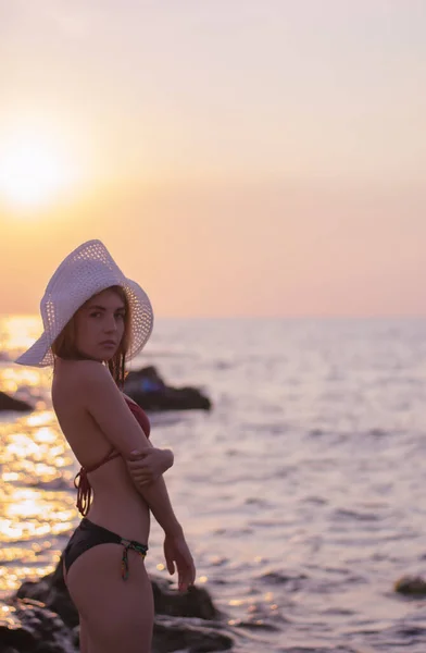 Egy gyönyörű fiatal nő portréja fürdőruhában a parton, egyedül a naplementében. — Stock Fotó