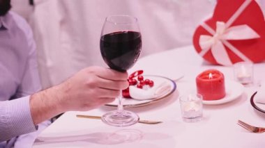 Toasting red wine glass in romantic dinner drinking at bar valentine day February 14