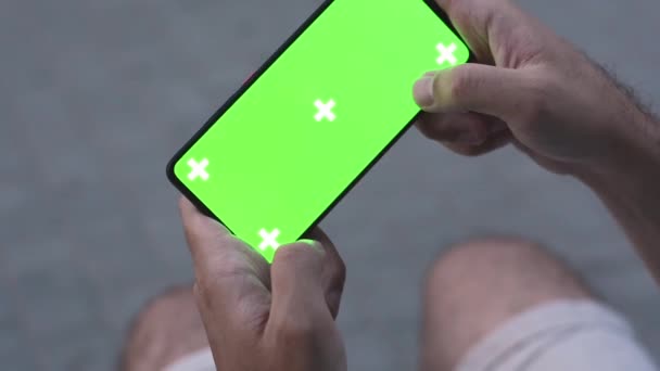 Zielony ekran dotykowy telefonu na ulicy w pobliżu budynku człowiek używa smartfona — Wideo stockowe