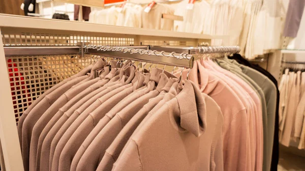 Percha ganchos en una ropa beage suéteres de punto con diferentes tamaños de tienda en grandes almacenes — Foto de Stock