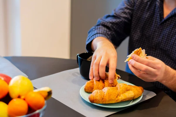 Primer plano de las manos de mesa de un joven comiendo deliciosa dieta croissant fragante comida nutricional — Foto de Stock
