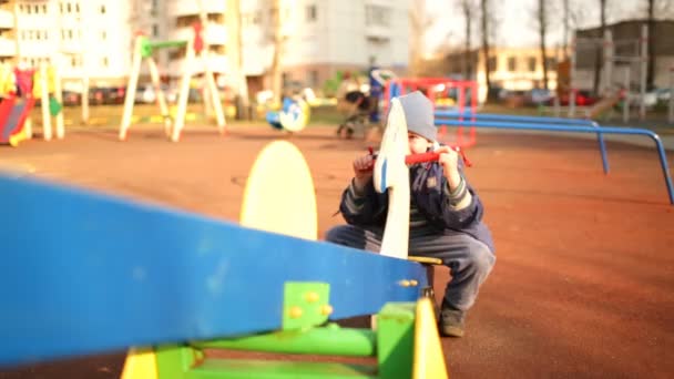 Cheerful boy in a blue dress on a swing. — Stock Video