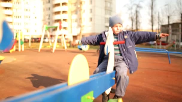 Wesoły chłopiec w niebieskim stroju na huśtawce. — Wideo stockowe