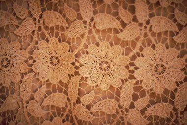 Kahverengi arkaplanda el yapımı tığ işinden yapılmış yaratıcı desen tasarımı.