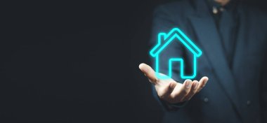 Emlak konsepti, iş adamı ev ikonu tutuyor. Ev elden gidiyor. Emlak sigortası ve güvenlik kavramı. İnsanın jestini ve evin sembolünü koruyorum.