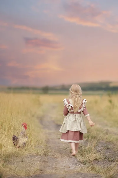 Dziewczyna Pięknej Sukience Spaceruje Polu Kogutem Trawie Tle Wzgórz Różowym — Zdjęcie stockowe