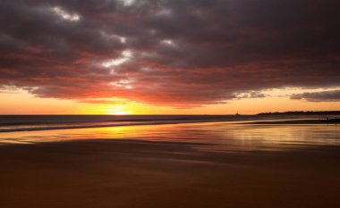 Gün doğumu Northumberland 'daki Blyth plajında başlıyor. St. Mary Deniz Feneri de uzakta.