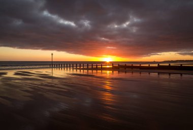 Gün doğumu Northumberland 'daki Blyth plajında başlıyor. St. Mary Deniz Feneri de uzakta.