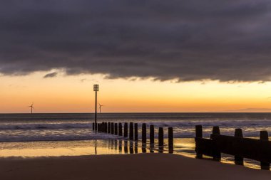 Gün doğumu Northumberland 'daki Blyth plajında başlıyor. St. Mary Deniz Feneri de uzakta.