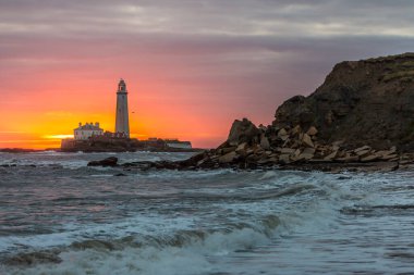 İngiltere 'nin kuzeydoğusundaki Whitley Körfezi' ndeki St. Mary Deniz Feneri 'nde muhteşem bir gün doğumu. Gökyüzü renk içinde patlıyor.