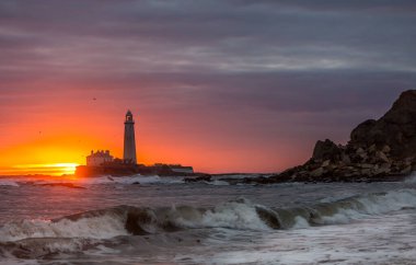 İngiltere 'nin kuzeydoğusundaki Whitley Körfezi' ndeki St. Mary Deniz Feneri 'nde muhteşem bir gün doğumu. Gökyüzü renk içinde patlıyor.