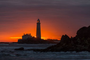 İngiltere 'nin kuzeydoğusundaki Whitley Körfezi' ndeki St. Mary Deniz Feneri 'nde muhteşem bir gün doğumu. Gökyüzü renk içinde patlıyor.