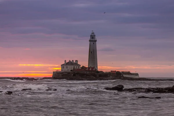 İngiltere 'nin kuzeydoğusundaki Whitley Körfezi' ndeki St. Mary Deniz Feneri 'nde muhteşem bir gün doğumu. Gökyüzü renk içinde patlıyor.