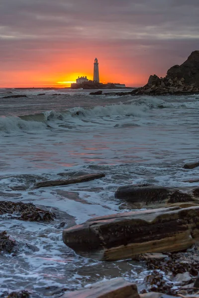 空が色で噴火するので 英国の北東部のウィットリー湾のセント メアリーズ灯台で壮大な日の出 — ストック写真