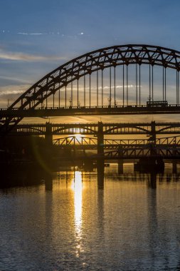 Günbatımında Tyne Köprüsü, İngiltere Newcastle 'ın altındaki neredeyse durgun Tyne Nehri' ne yansıyor.