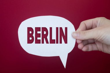 Speech bubble in front of colored background with Berlin text.
