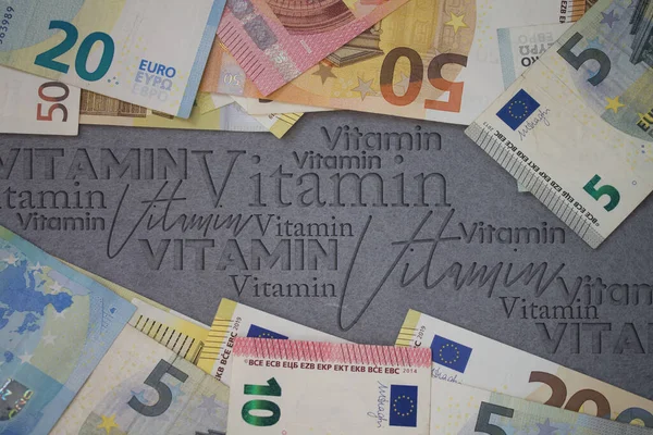 Vitamin word with money. Paper currency background with different banknotes.