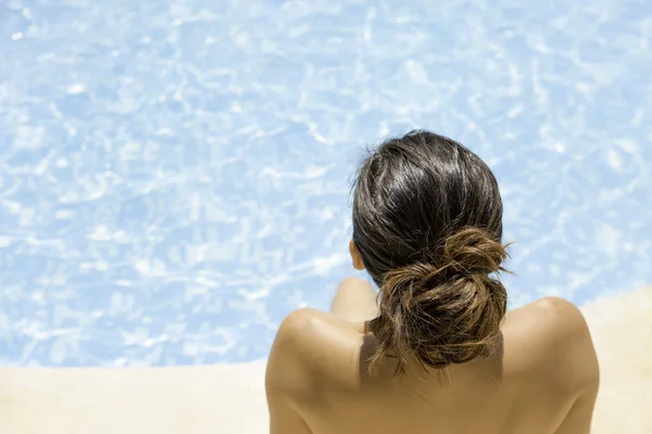 Молодая женщина сидит на краю бассейна — стоковое фото