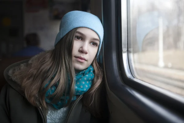 Девочка-подросток сидит в вагоне и смотрит в окно. — стоковое фото