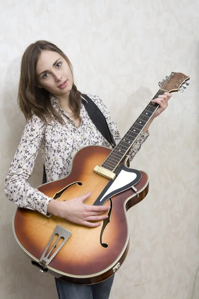 Jovem atraente tocando guitarra em fundo cinza — Fotografia de Stock