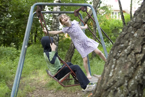 Crianças balançando em um balanço — Fotografia de Stock