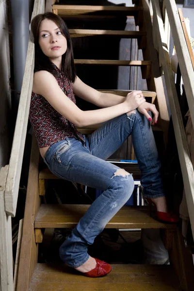 Jovem atraente sorridente menina em jeans ter um buraco sentado em — Fotografia de Stock