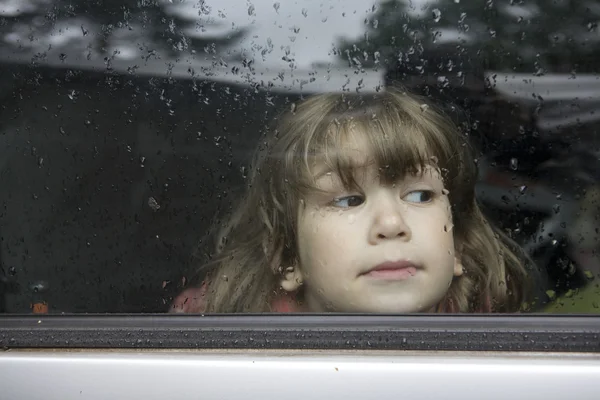 Portrait young girl looking through window — Stock Photo, Image