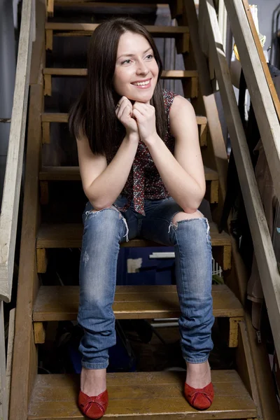 Genç çekici gülümseyen kız kot pantolon oturan bir delik — Stok fotoğraf