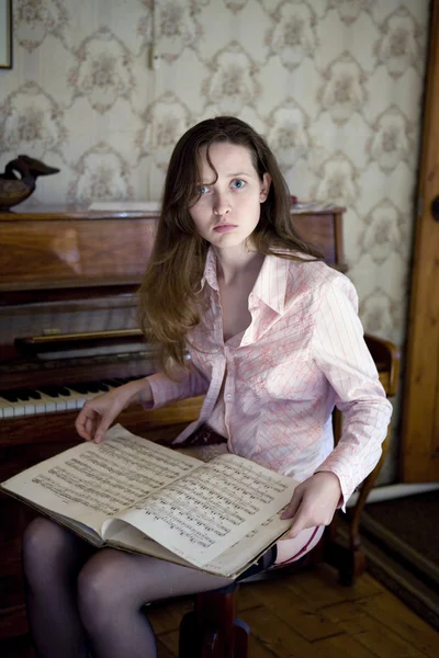 Piyanonun üzerinde oturan genç kadın — Stok fotoğraf