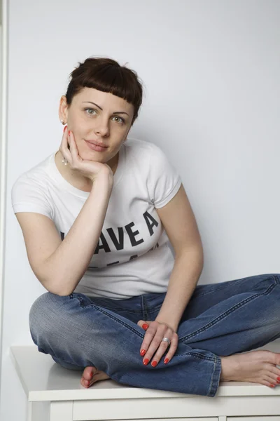 Pensive woman sitting on table — Stock Photo, Image